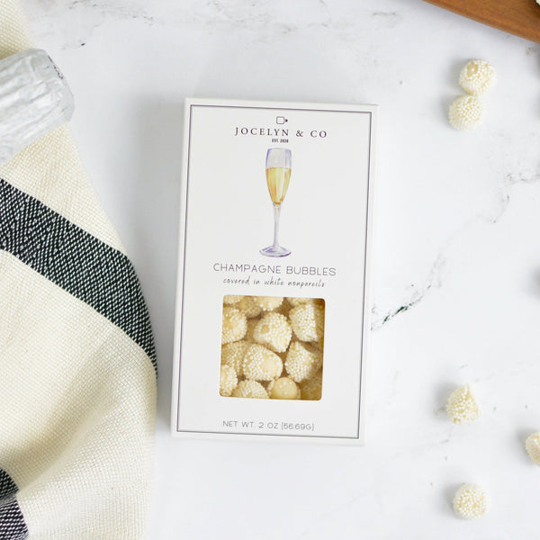 Jocelyn & Co. Champagne Bubble Gels candy in signature packaging on marble surface with decorative items