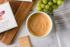 Cheese spread in a bowl with crackers and grapes on a marble surface